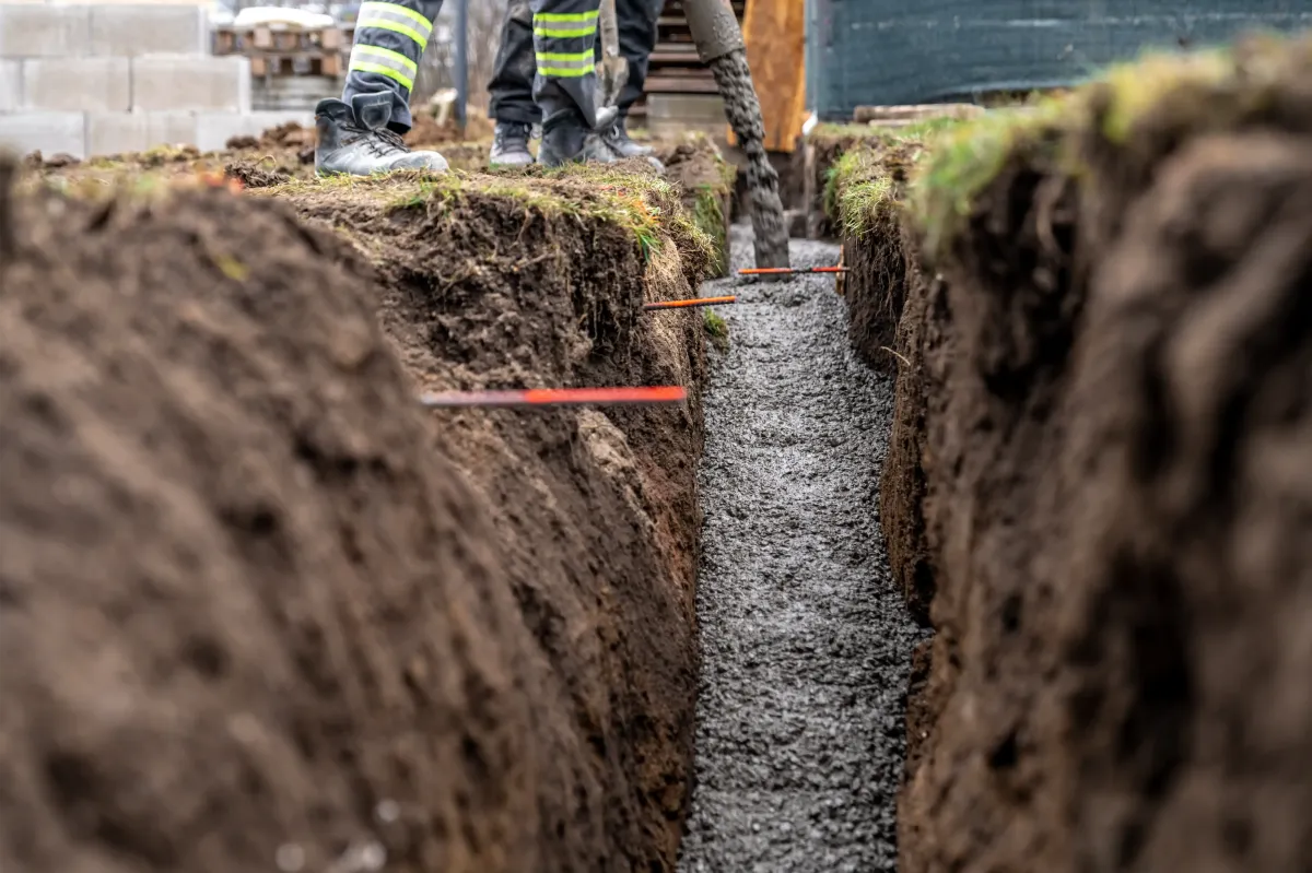 Professional drainage solutions in Glenshaw, PA – Image of a trench being filled with gravel and concrete for a high-quality drainage system installation. Proper drainage prevents water damage and erosion, ensuring long-lasting landscape stability. Contact us for expert drainage solutions in Glenshaw.