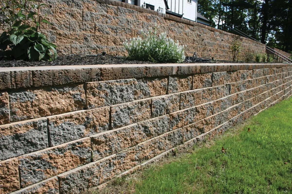 Custom stone retaining wall with green plants, enhancing landscape design and functionality for outdoor spaces.