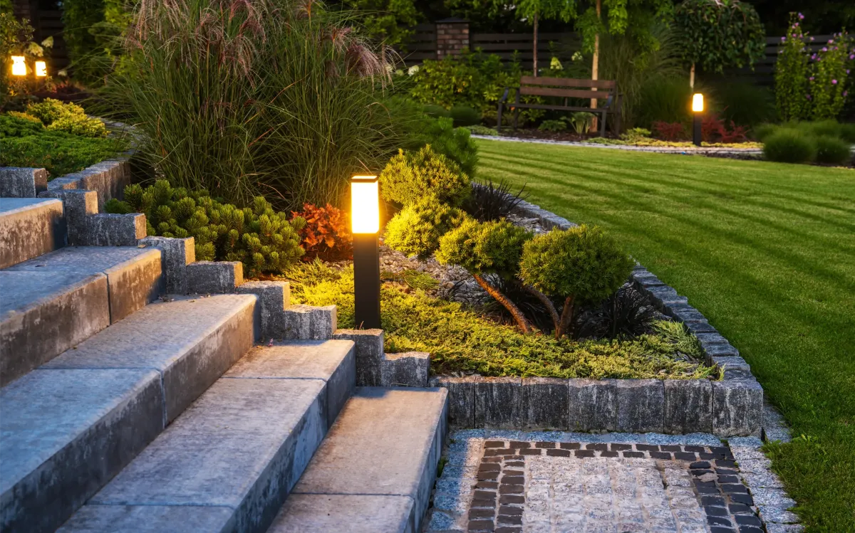 Elegant outdoor lighting and landscaping in Glenshaw, PA. Features stone steps, lush greenery, and illuminated pathways for a stunning backyard retreat.
